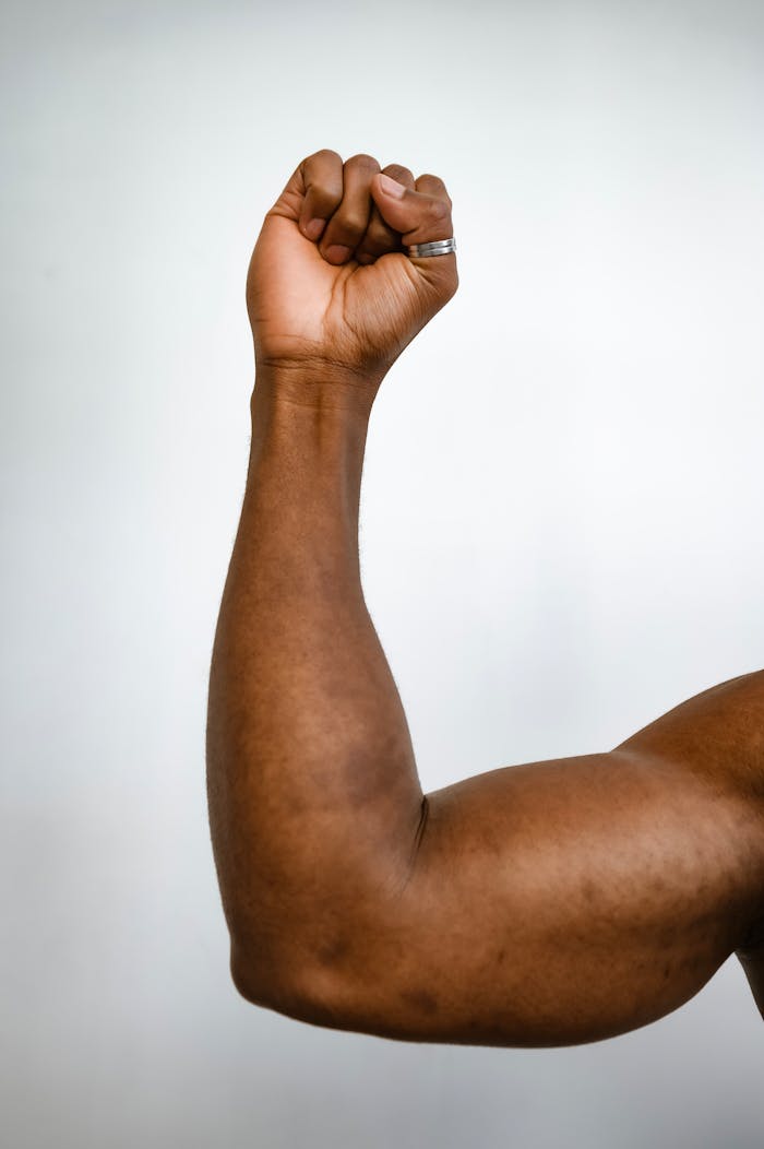 Vertical shot of a muscular arm showing strength with a clenched fist.